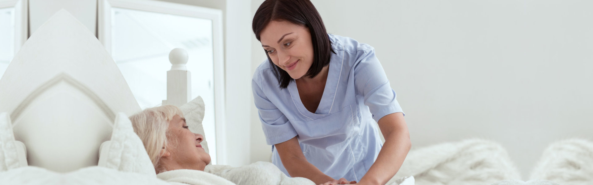 woman smiling with senior in bed