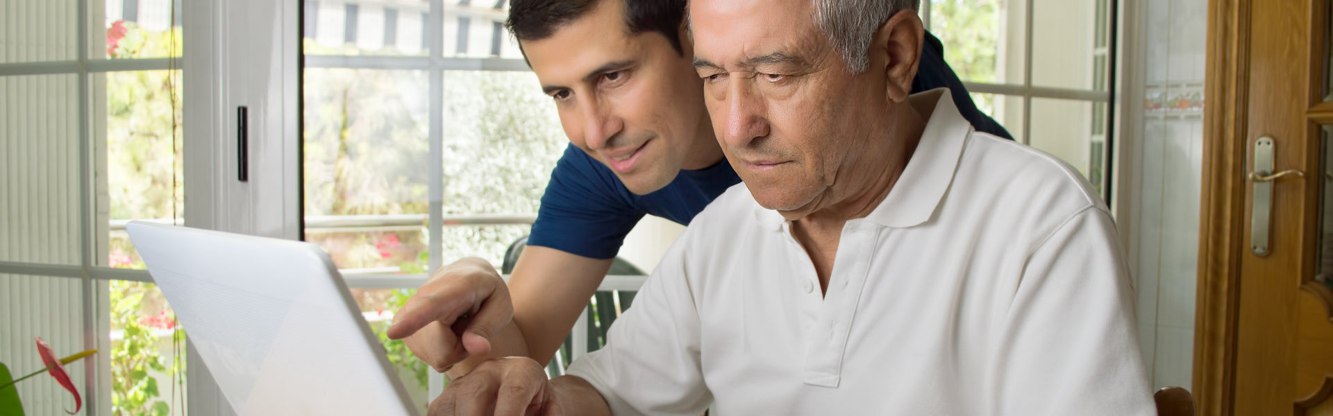 man and senior looking in computer